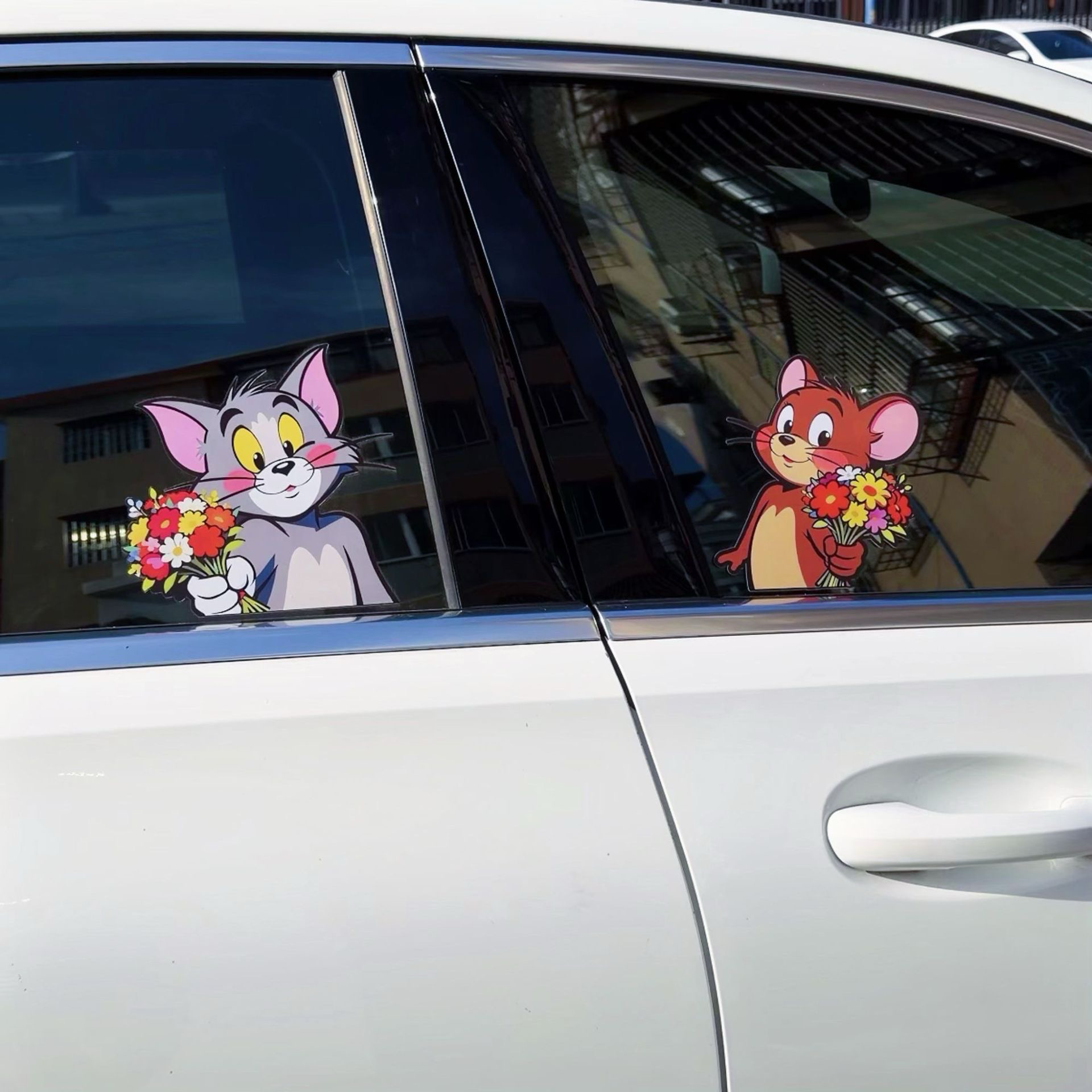 Playful Tom and Jerry 3D decals positioned on the side passenger window of a white car.