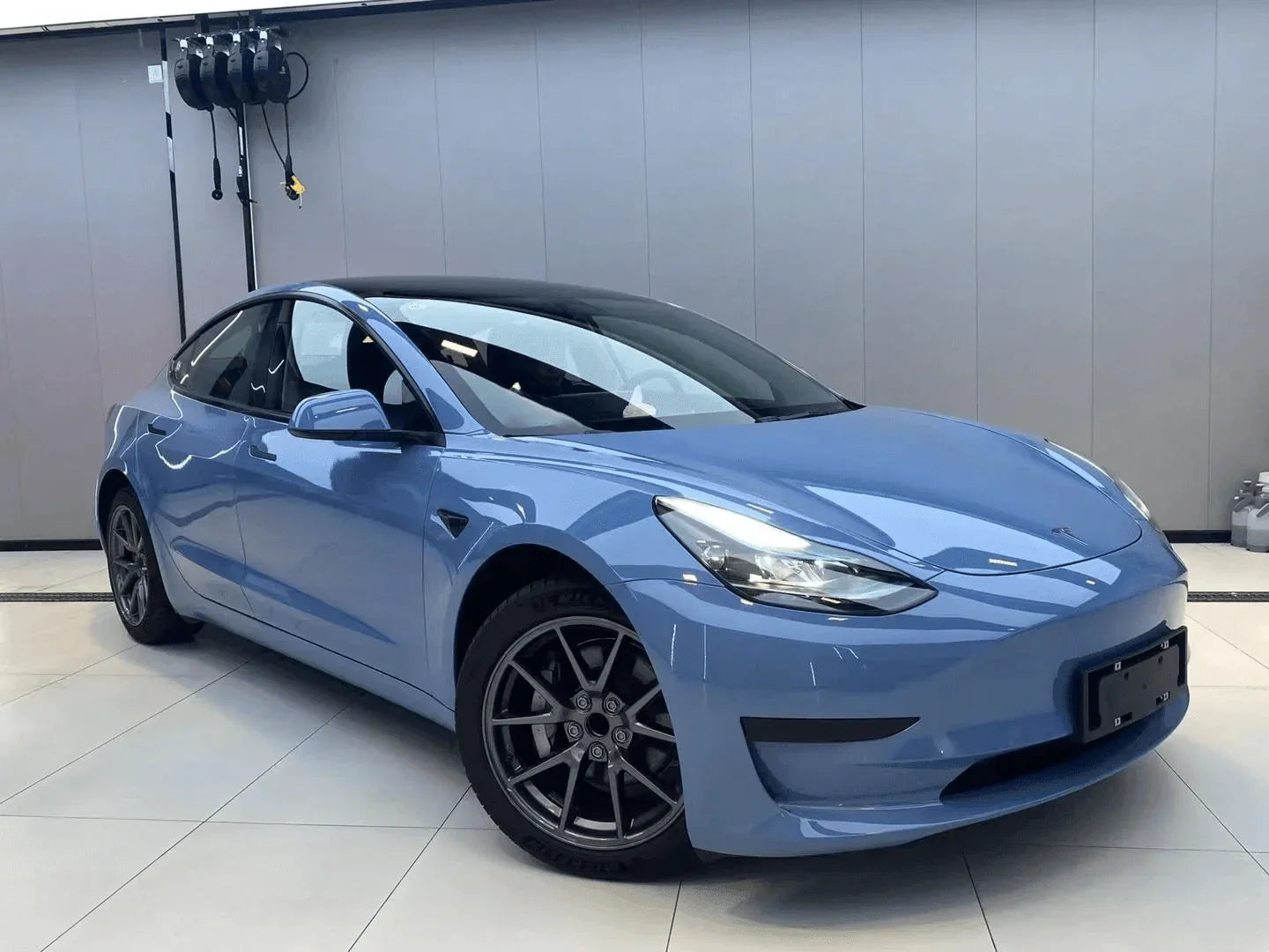 Blue car on a white floor with a gray wall background