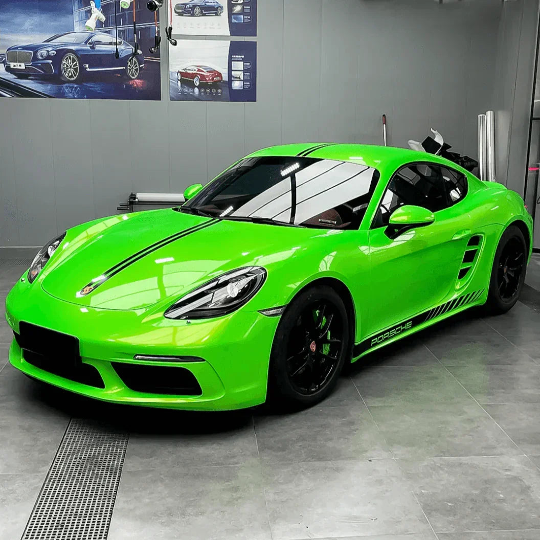 Green sports car in a showroom with posters on the wall.