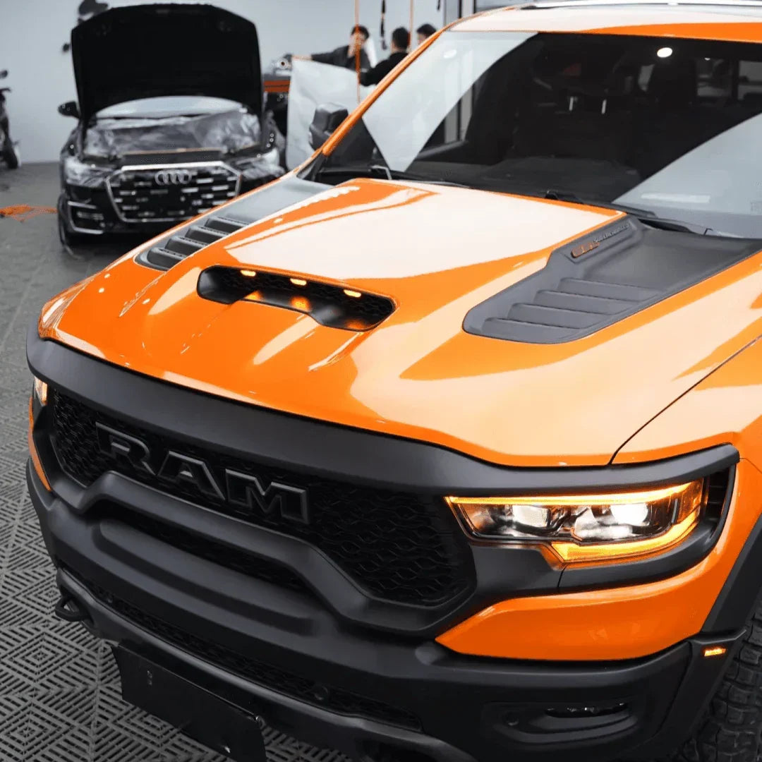 Orange and black Ram truck in a showroom setting