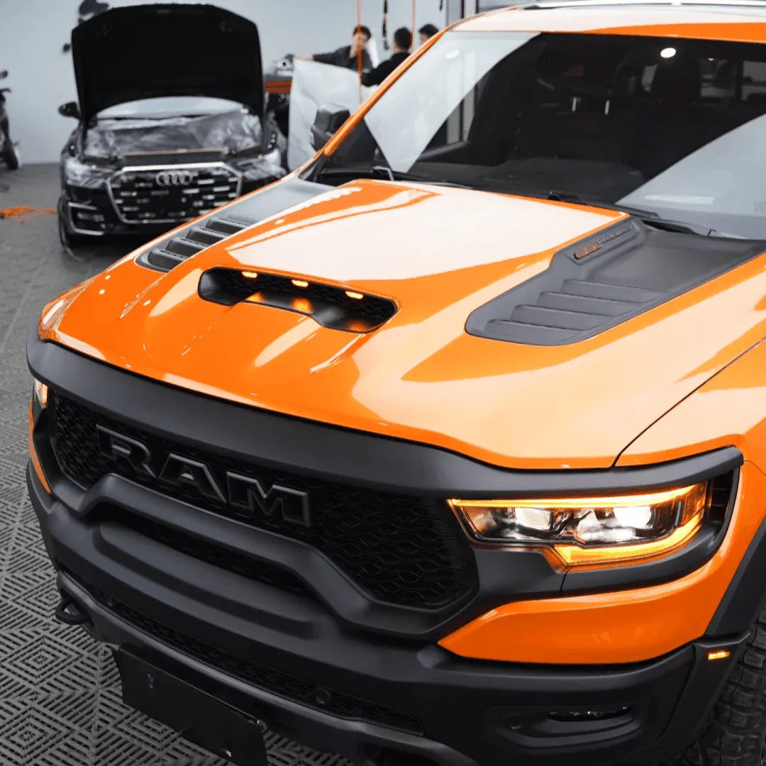 Orange and black Ram truck in a showroom setting
