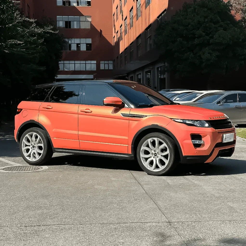 Orange Range Rover Evoque parked on a street with buildings in the background