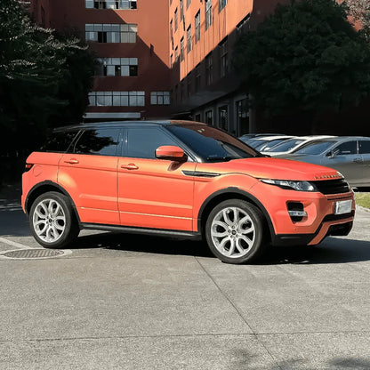 Orange Range Rover Evoque parked on a street with buildings in the background