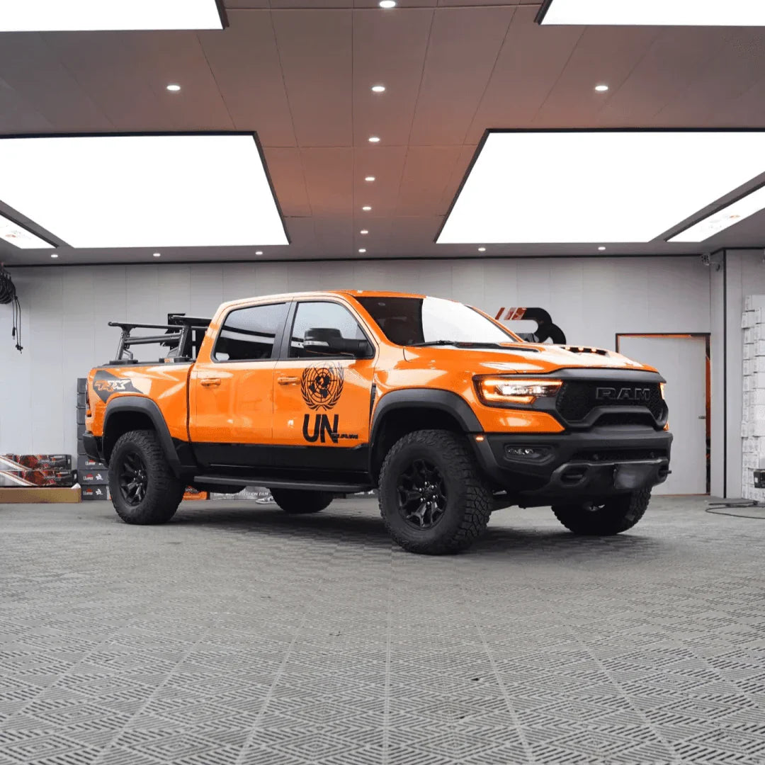 Orange pickup truck with black accents in a showroom setting