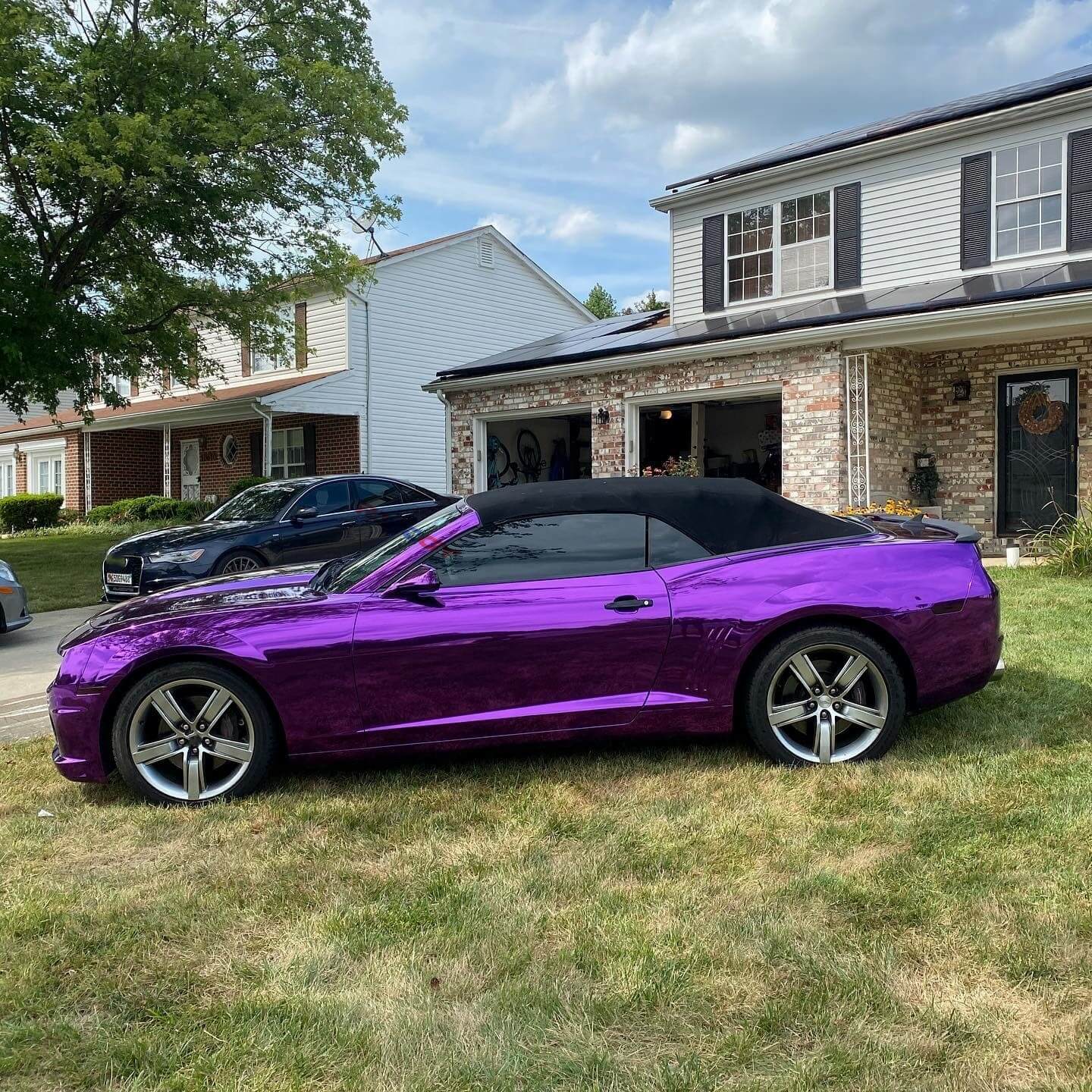Purple convertible car parked in a driveway with a house in the background